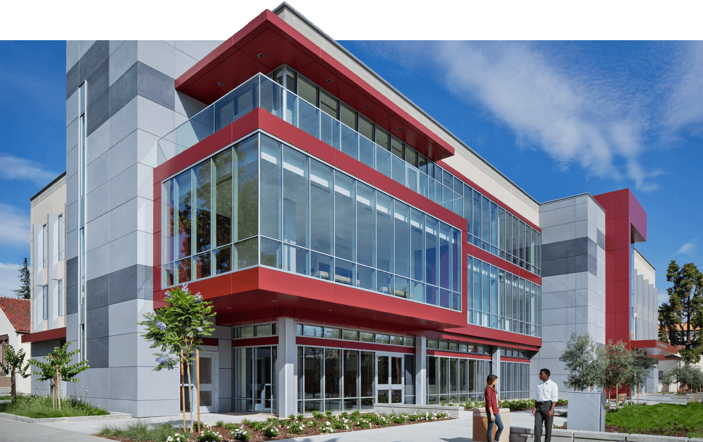 Large office building exterior, gray walls with red trim and floor-to-ceiling windows