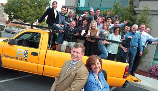 Blach Construction employees in orange truck with clients
